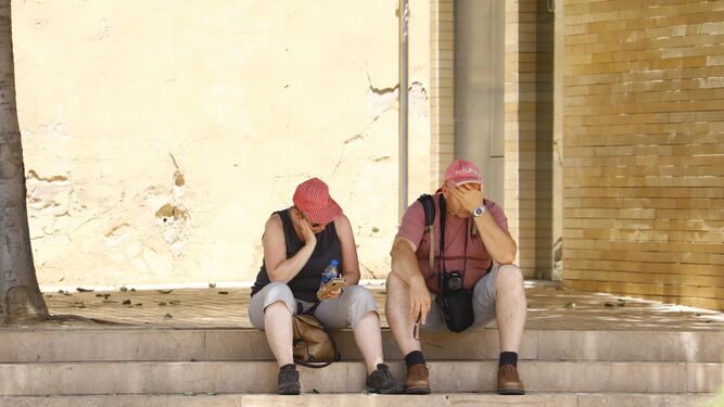 Unos turistas sofocados por el calor descansan a la sombra en el centro de Córdoba.