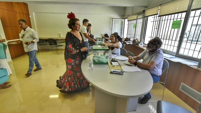 Una mujer vota en Algeciras, donde la feria coincide con las elecciones, vestida de flamenca.