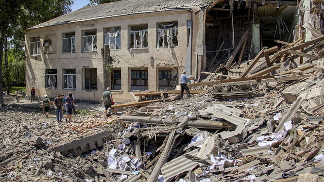 Lugareños limpian los escombros tras un ataque con misiles en una pequeña localidad cercana a Jarkov.