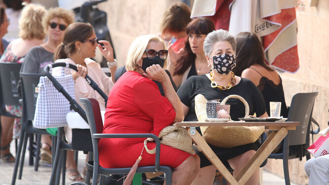 Mujeres con y sin mascarillas en una terraza de Almería.