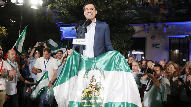 El presidente Juanma Moreno sostiene una bandera de Andalucía tras su victoria electoral, el pasado domingo 19.