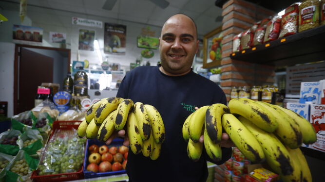 Un frutero cordobés muestra dos piñas de plátanos.