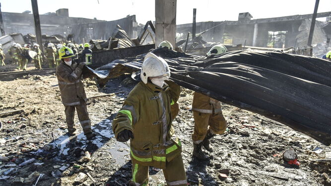 Bomberos retiran escombros del centro comercial atacado en Kremenchuk.