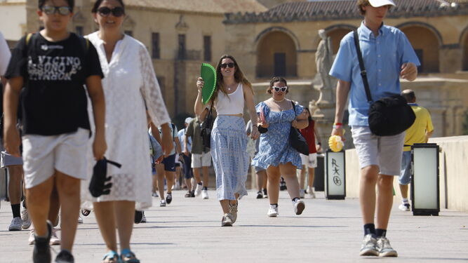 Varias personas caminan por el Puente Romano de Córdoba.