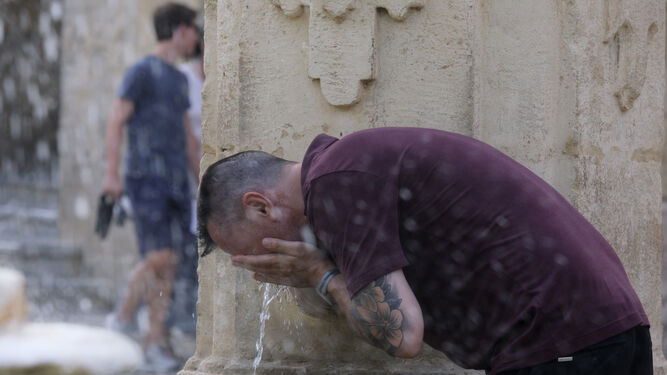 Una persona se refresca en una fuente en Córdoba.