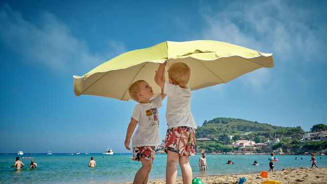 Niños abriendo una sombrilla en la playa