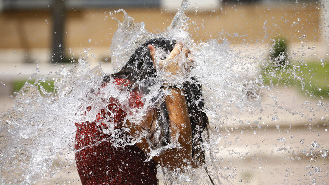 Una joven se refresca en una fuente en Córdoba.