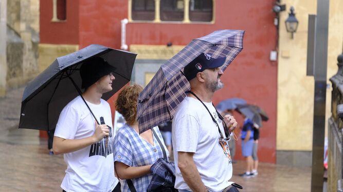 Una familia de turistas, bajo los paraguas.