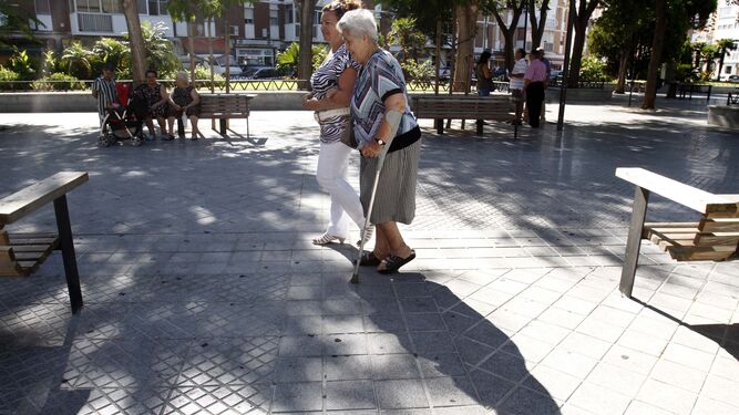 Una trabajadora de ayuda a domicilio acompaña a una mujer mayor en un paseo.