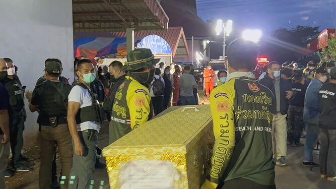 Trabajadores de los equipos de rescate portan los féretros con los cuerpos de las víctimas.