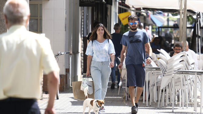 Una mujer y un hombre pasean con su perro por una calle de la capital.