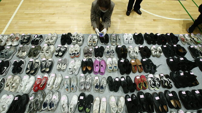Una oficial de policía revisa uno de los pares de zapatos rescatados de la escena de la estampida en un pabellón deportivo de Seúl.