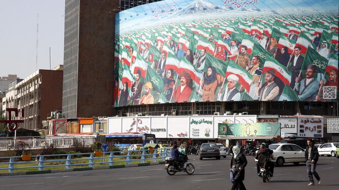 Viandantes pasan ante un mural en Teherán.