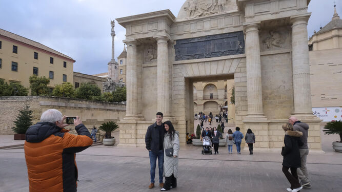 Una joven pareja de turistas posa para una foto en la Puerta del Puente.