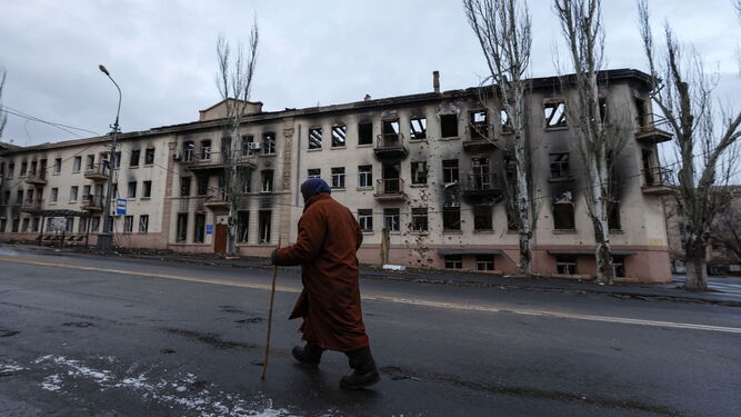 Una persona camina ante un edificio dañado en Mariupol.