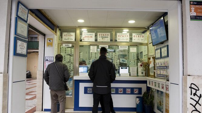 Varias personas aguardan en una administración de loterías.