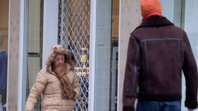 Dos personas caminan por Córdoba protegidas con ropa de abrigo por el frío.