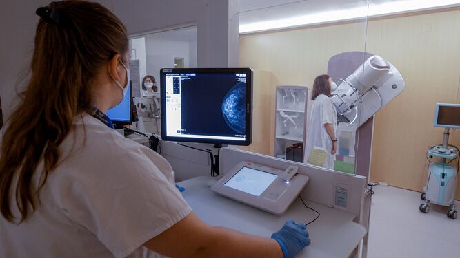Una profesional sanitaria realiza una mamografía a una mujer.