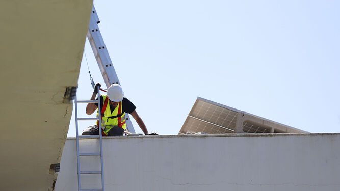Un trabajador instala placas solares en un edificio.