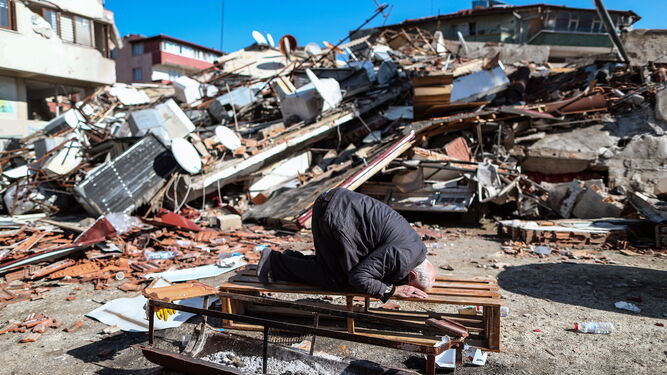 Un hombre reza ante un edificio totalmente destruido en Hatay, Turquía.