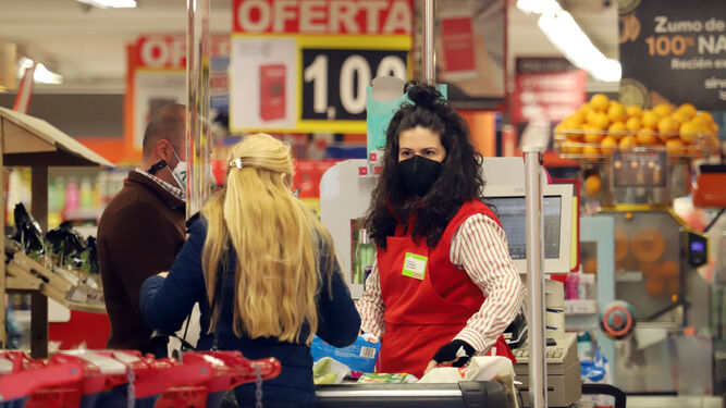 Una cajera de un supermercado atiende a dos clientes.