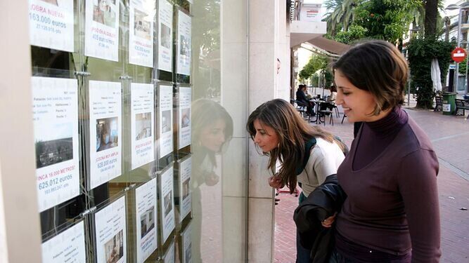 Dos jóvenes observan anuncios en una inmobiliaria