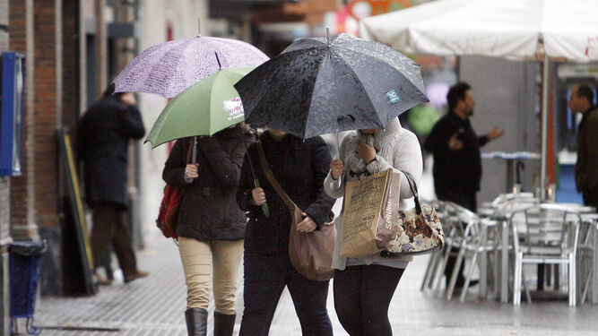 Varias personas se protegen de la lluvia bajo paraguas.