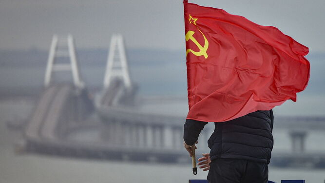 Un hombre coloca una bandera soviética ante el puente de Crimea.