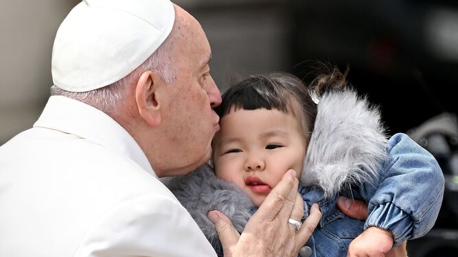 El papa Francisco besa a un niño al final de su audiencia general semanal en la Plaza de San Pedro.