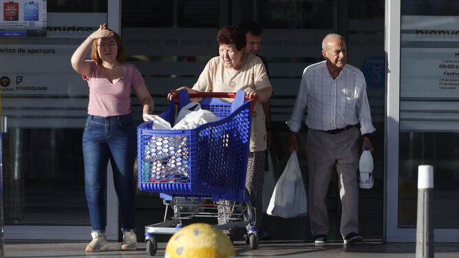 Varias personas salen de un supermercado con la compra.