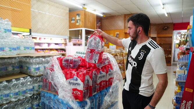 Un joven coge un paquete de agua embotellada en un supermercado de Pozoblanco.