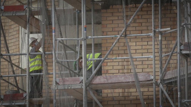 Obreros de la construcción junto a un andamio en las obras de un edificio.