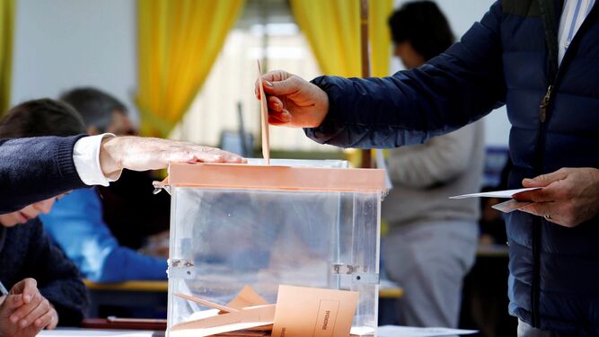 Un hombre introduce su papeleta en una urna  de un colegio electoral.