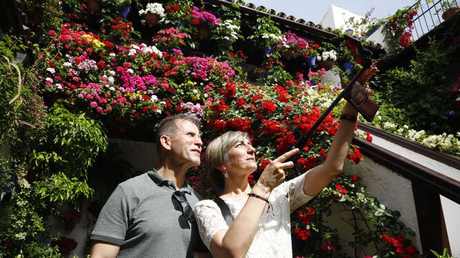 Dos turistas se hacen un selfi ante las cascadas de flores del patio de San Basilio, 44.