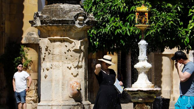Una turista se refresca en la fuente del Patio de los Naranjos de Córdoba.