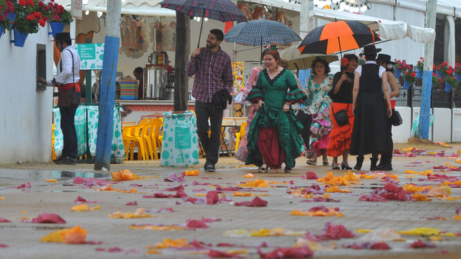 Varias personas se protegen de la lluvia en la Feria de Córdoba.
