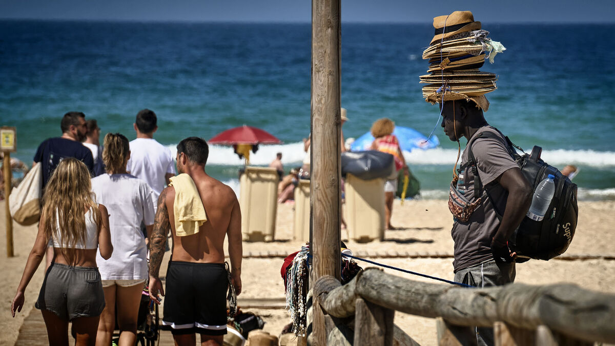 Varios bañistas en las playas de la capital gaditana mientras pasa un vendedor ambulante.