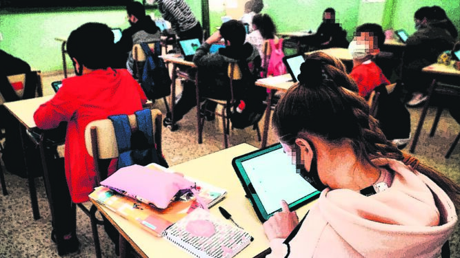 Alumnos con dispositivos digitales en una clase.