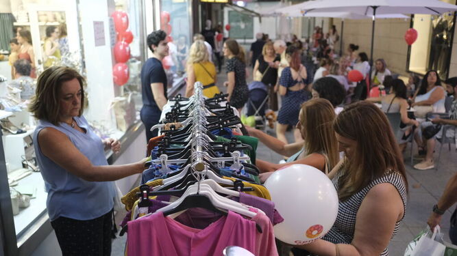 Numerosas personas observan las prendas de ropa de una tienda en la Shopping Night de 2022.