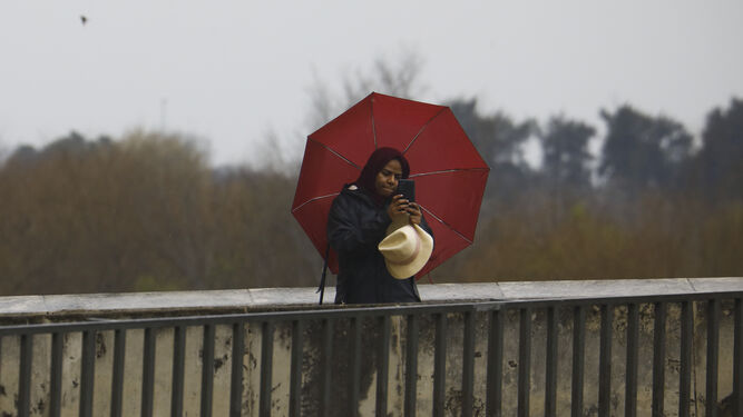 Una mujer se protege de la lluvia con su paraguas.