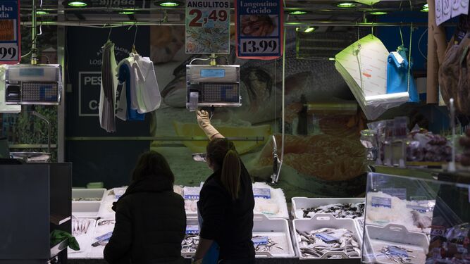 Una pescadera atiende a una clienta en una pescadería de un mercado.