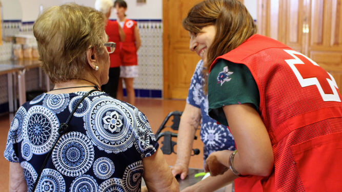 Una voluntaria de Cruz Roja acompaña a una mujer mayor.
