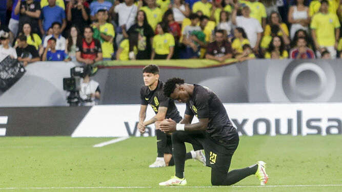 Vinícius, todo vestido de negro como el resto de Brasil, denuncia de rodillas el racismo.