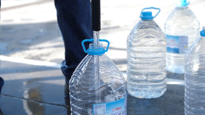 Una persona rellena varias garrafas con agua potable.