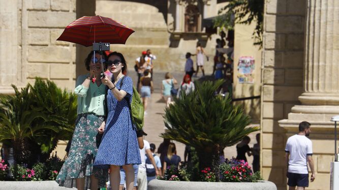 Unas turistas se protegen del sol mientras pasean por el centro de Córdoba.