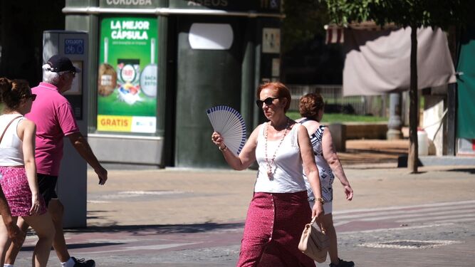 Una mujer se abanica mientras cruza un paso de peatones de la capital.