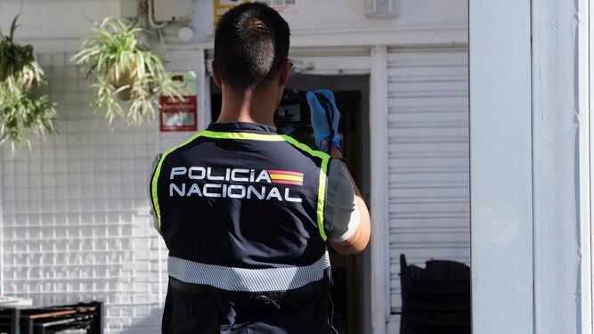 Un agente de la Policía Nacional fotografía la entrada del bar en el que ocurrieron los hechos.