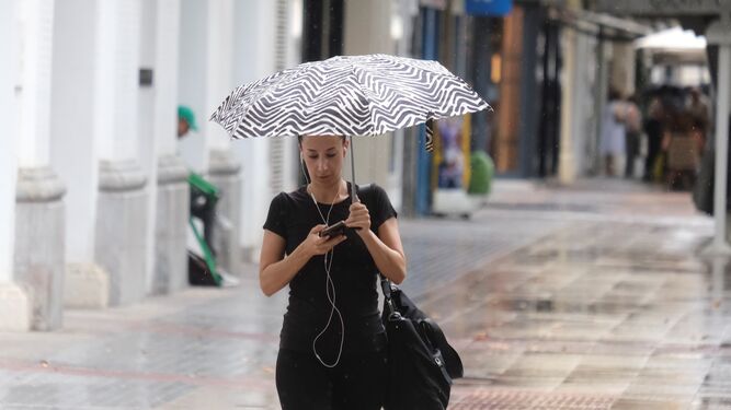 Una joven bajo un paraguas en el centro de Córdoba.