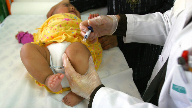 Una sanitaria vacuna a una bebé.