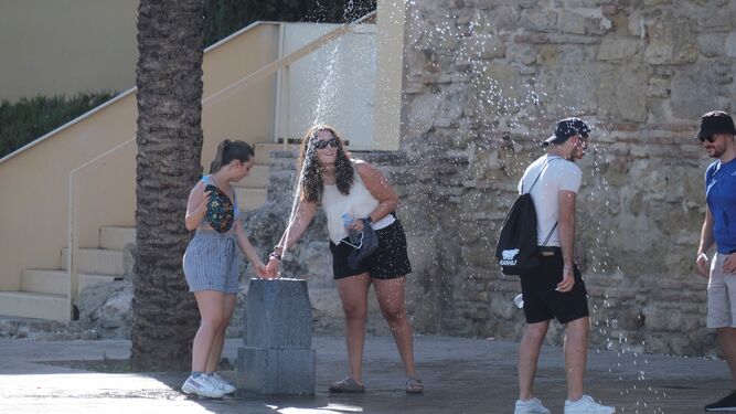 Varias personas se refrescan con una fuente en el entorno de Puerta del Puente.